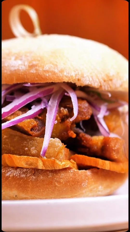 Sánguche de chicharrón de Nazca: costilla de cerdo confitada, boniato y salsa criolla en pan crocante